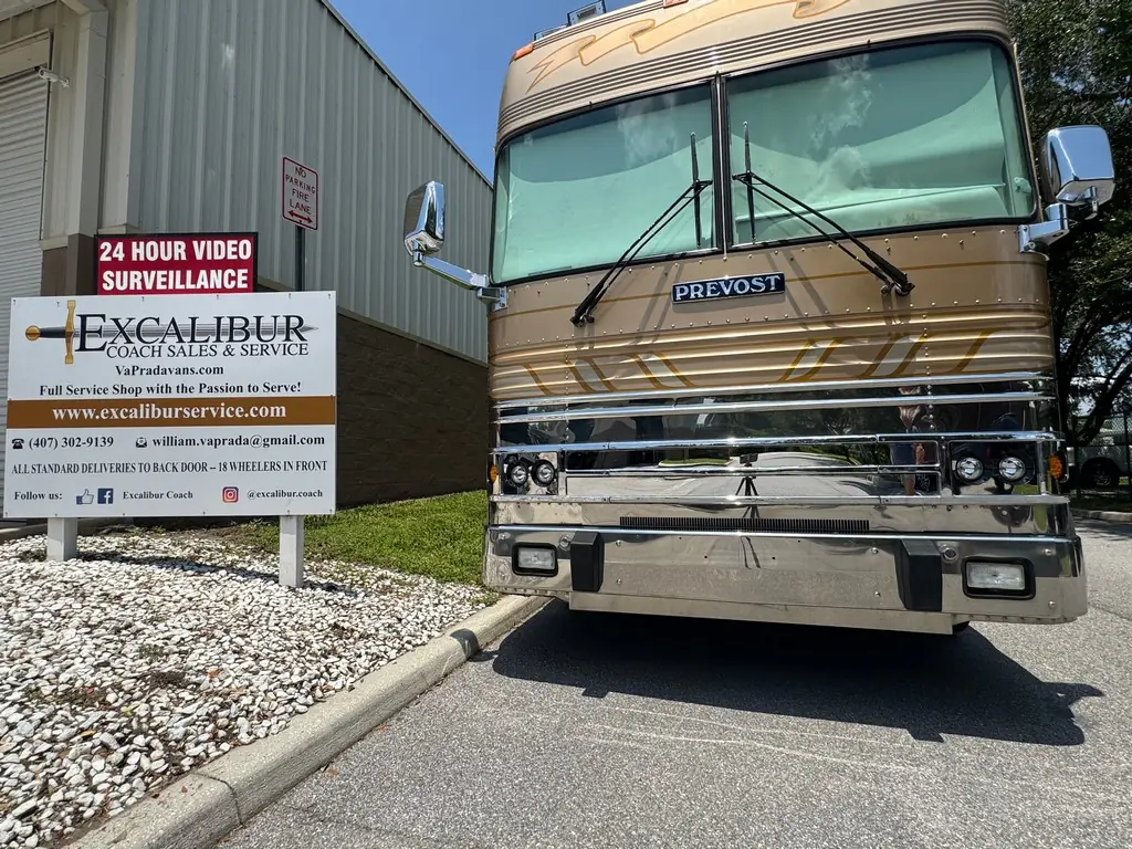 A Prevost coach parked in front of the Excalibur Coach Sales & Service sign in Sanford, Florida